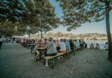 People sit on the lawn and listen to musicians on a small stage © Koblenz-Touristik, Janko.Media
